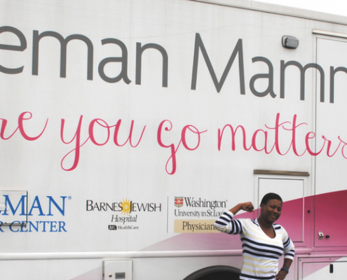 Woman smiling and flexing in front of Siteman Mammogram bus