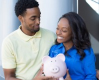Man and woman smiling while holding a piggy bank.