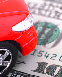 Image of small red car sitting atop money