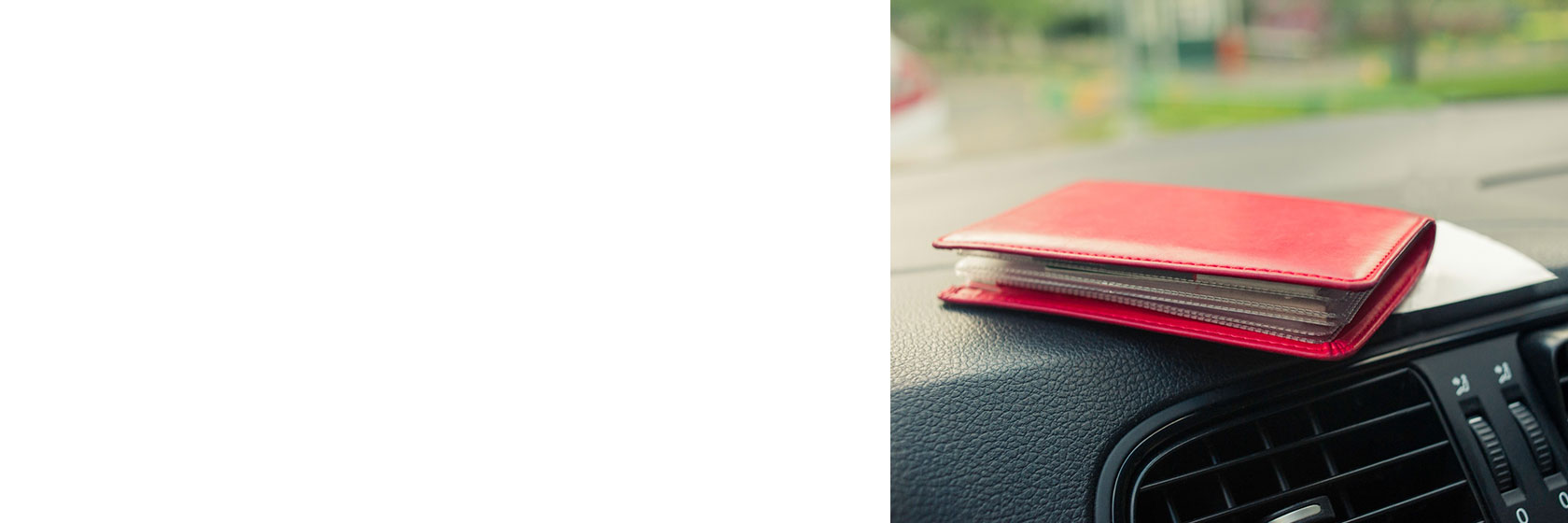 Image of a red wallet sitting atop a vehicle dashboard. 