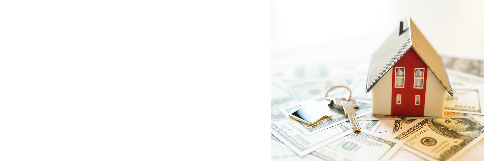 tiny home next to a key on top of dollar bills.