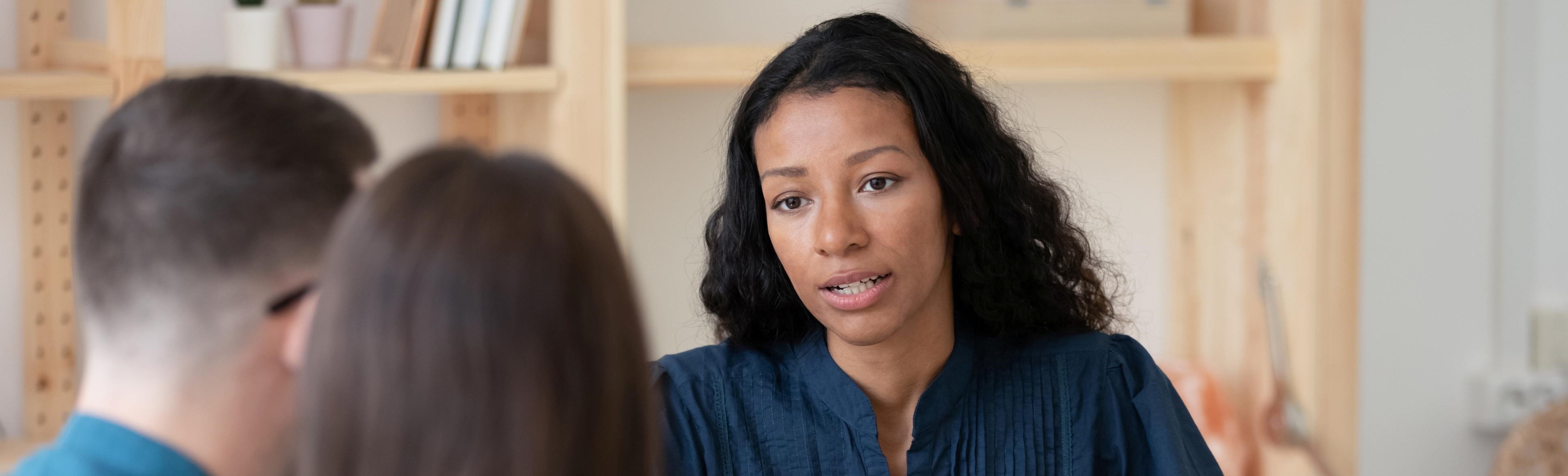 woman talking to couple at a desk