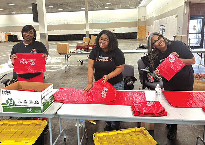 Image of 3 Slccu employees prepping supplies for assistance wearing shirts that say "Mission Giveback"